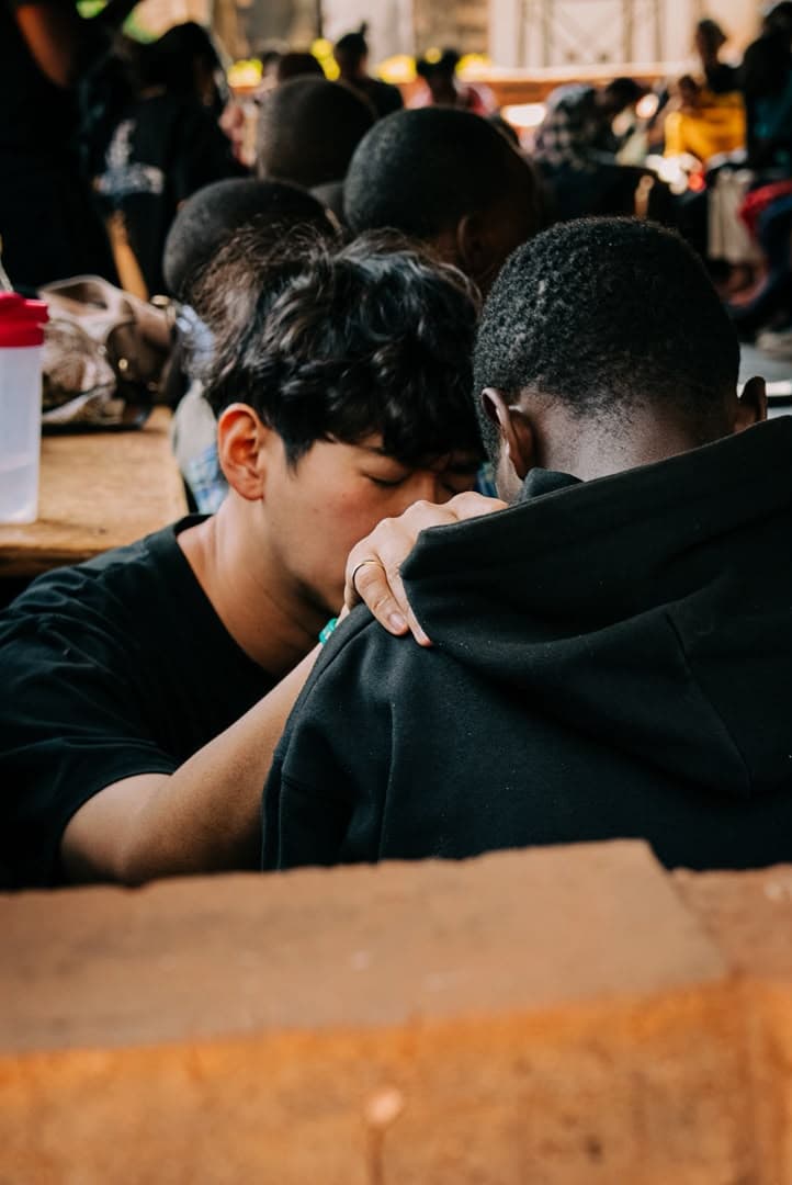 A Go Africa team member praying personally with another young man