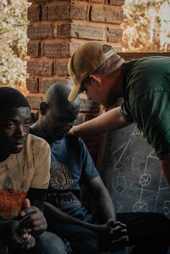 A Go Africa team member praying with a young man
